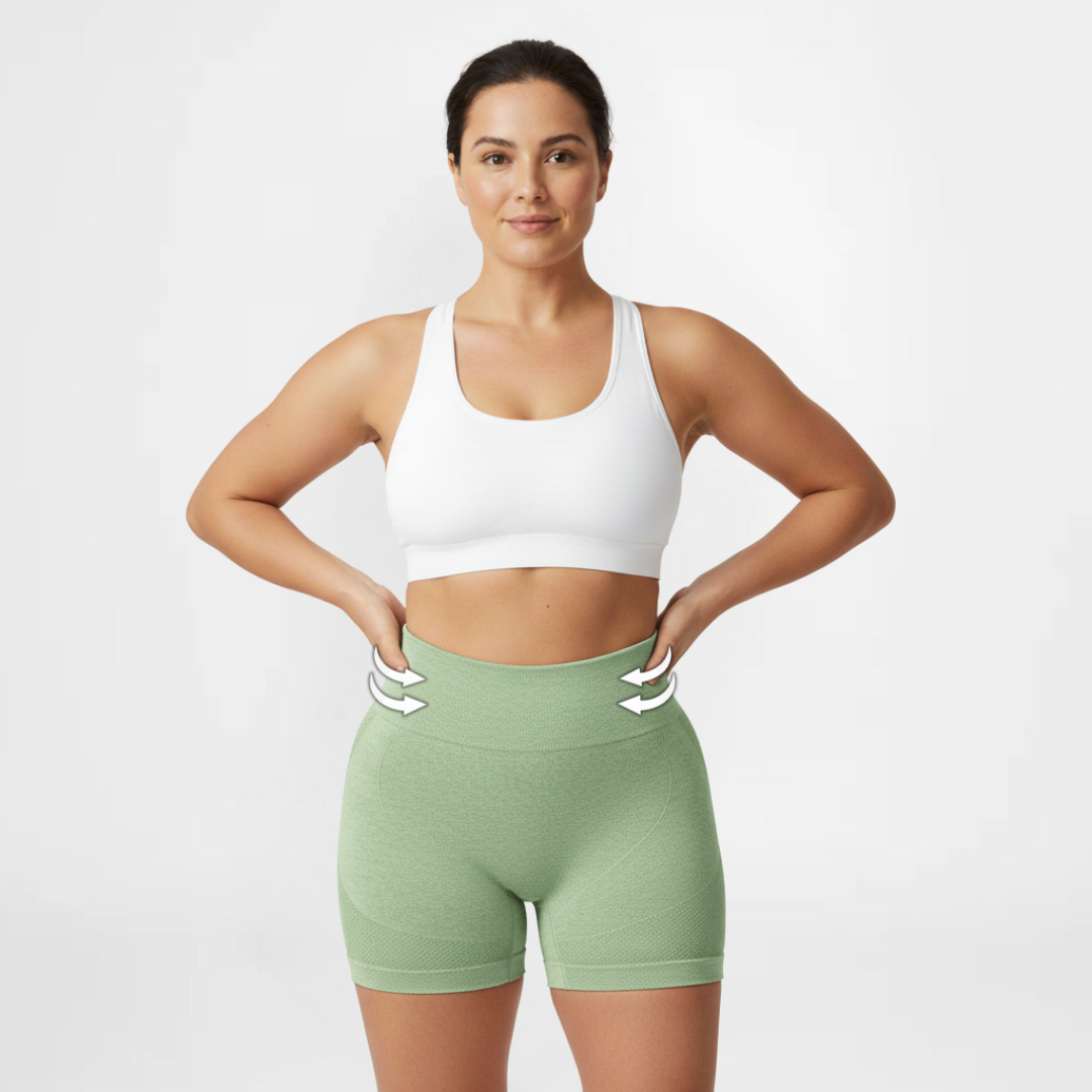 Woman wearing a white sports bra and green shorts on a light gray background