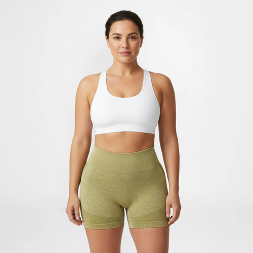 Woman wearing a white sports bra and green shorts on a white background