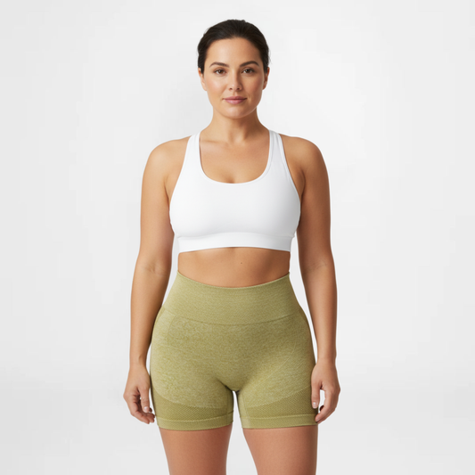 Woman wearing a white sports bra and green shorts on a white background