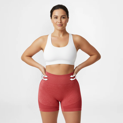 Woman wearing a white sports bra and red high-waisted shorts on a light gray background